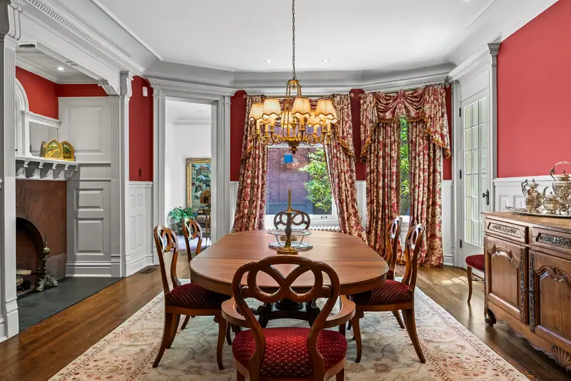 Red dining room with wainscoting and brick fireplace