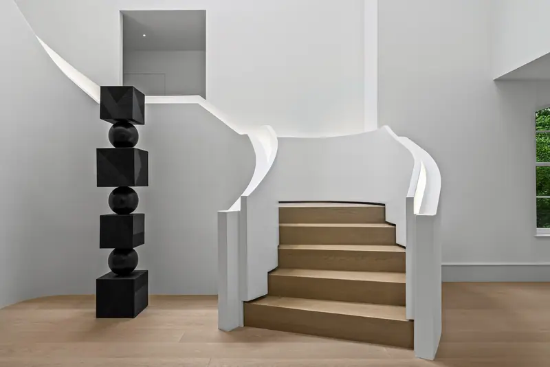 Curved white staircase with sculpture