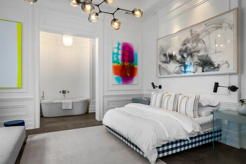 Primary bedroom with contemporary art and a freestanding tub beyond