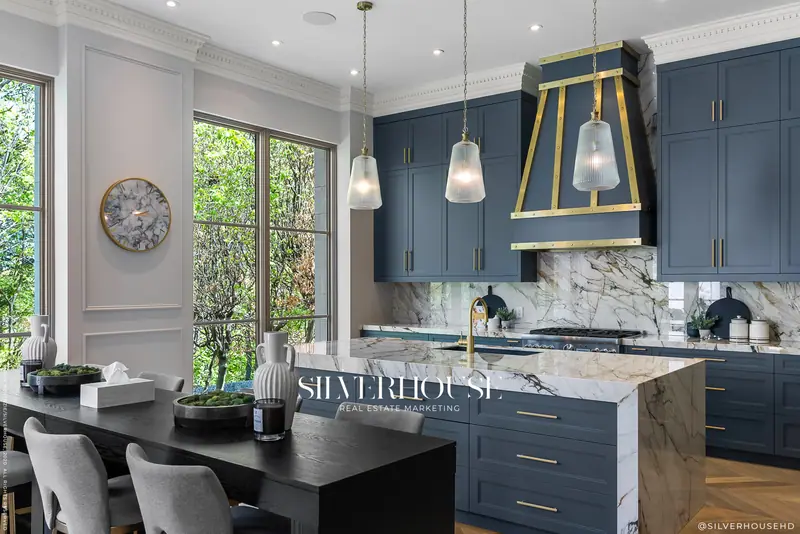 Blue kitchen with brass hood and marble island