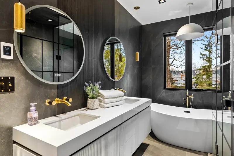 Black-tiled ensuite with round mirrors and freestanding tub
