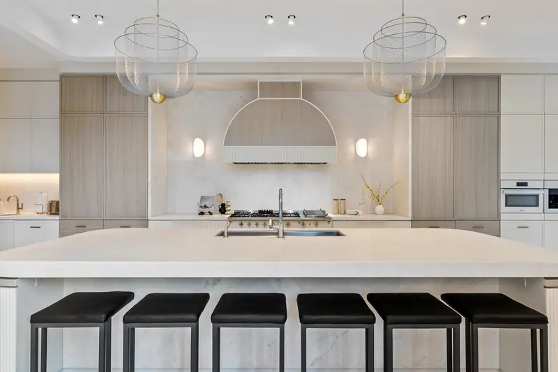 Chef's kitchen with curved island, sculpted hood and glass pendants